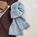 Blue and white chunky knit wool scarf with brand tag on a warm winter coat background - Creamy Blue