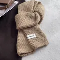 Detail of chunky knit khaki scarf texture with a white woven brand label on the corner - Off White