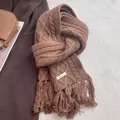 Macro detail of caramel 100% wool scarf showing cable knit texture and soft fringe - Coffee
