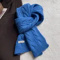 Detail of blue cable-knit texture and 100% wool label on premium winter scarf - Blue
