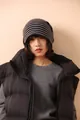 Dettaglio del berretto in maglia a righe abbinato a un gilet di piumino nero con cappuccio - Riga Nero Grigio