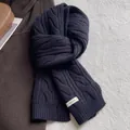 Détail de l'étiquette 100% laine sur une écharpe torsadée bleu foncé pour femme - Noir