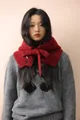 Dettaglio di un passamontagna rosso in maglia di lana con fiocco e bottone nero nero - Rosso