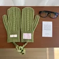 Detailed close-up of avocado green cable knit mittens with a neck strap on a wooden desk - Cable Knit Neck Strap Style / Matcha Green