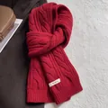 Gros plan d'une écharpe rouge 100% laine avec maille torsadée et étiquette de matière - Rouge