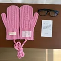 Flat lay of pink cable knit mittens with a neck strap on dark wood texture background - Cable Knit Neck Strap Style / Sakura Pink
