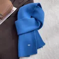 Detail eines königsblauen Rippstrickschals aus 100% Wolle mit Metallmarkenanhänger - Königsblau