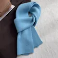 Nahaufnahme hellblauer Strickschal aus 100% Wolle mit Rippenmuster und Logo-Aufnäher - Gletscherblau