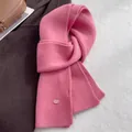 Detail of ribbed knit pink wool scarf with a branded tag on a cozy winter coat - Rose