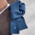 Detail der dunkelblauen Wollschal-Rippenstruktur mit kleinem blauen ovalen Logo-Patch - Marineblau