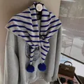Detail of blue and white striped knit shawl with pom-poms on light grey sweatshirt - Blue