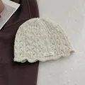 Detailed close-up of cream wool knit beanie featuring hollow texture and 100% wool label - Off White