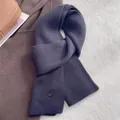 Detailed macro view of the soft ribbed knit texture and navy wool scarf with metal hardware - Aqua