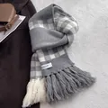 Detailed macro view of the knitted checkered scarf texture with fine fringe and brand label - Silver Gray