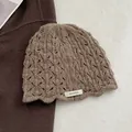 Macro shot of brown 100% wool crochet beanie showing intricate hollow floral patterns - Khaki