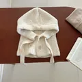 Texture de maille détaillée d'une cagoule en laine blanc crème avec boutons sur bois - Crème