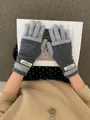 Close-up of contrast grey knit gloves with warm ribbed cuffs and brand logo detail - Gray
