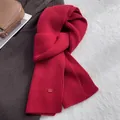 Detailierte Textur des roten Strickschals aus Wolle mit hochwertigem Logo-Abzeichen - Weihnachtsrot