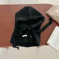 Détail de la cagoule en maille noire avec fermeture à bouton et texture tricotée nette - Noir