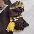 Detail of checkered knit scarf with tassels and brand label on a cozy coat - Yellow