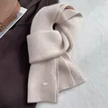 Detailed close-up of beige wool scarf featuring ribbed texture and metal brand tag - Off White