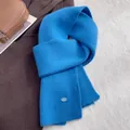 Detail eines gletscherblauen Wollschals mit Rippenstrick und dekorativem ovalem Knopf - Königsblau