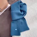 Nahaufnahme des blauen Wollstrickschals mit vertikaler Rippenstruktur und ovalem Etikett - Marineblau