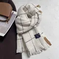 Detalle de bufanda de cuadros beige con flecos, etiqueta de cuero y textura suave de lana - Marfil
