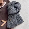 Dettaglio trama di sciarpa in lana grigio scuro con maglia a trecce e etichetta brand - grigio scuro