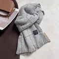 Detalle de bufanda de cuadros grises con flecos gruesos y etiqueta de tela de calidad - Gris claro