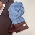 Close-up of blue cable knit scarf with brown ribbed edge and white fabric brand label - Blue and Coffee