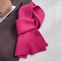 Detail of rose red knit wool scarf with ribbed texture and small oval decorative button - Scarlet