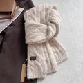 Close-up of cable knit wool scarf texture with brand tag on neutral winter coat background - Twist Pattern / Cream Rice