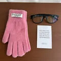 Detailed view of pink knitted touchscreen gloves with branding label on wooden background - Pink