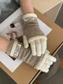 Detail shot of oatmeal and white layered knit gloves with brand woven label on the wrist - Milk Tea