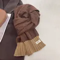 Detail of chunky cable knit scarf in brown and khaki with a neat decorative cloth label - Coffee & Khaki