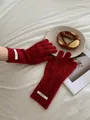 Detail of red merino wool gloves featuring knitted diamond pattern and brand label - Red