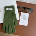 Detail of green knitted thermal glove with woven label on wooden table setting - Green