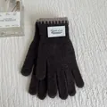 Detail of dark coffee knit gloves featuring contrast edge stitching and a white brand label - Coffee