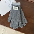 Detail of grey knitted gloves with Silent Wind woven label on dark wooden background - Gray