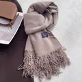 Dettaglio della sciarpa pashmina color cammello scuro con nappe lunghe ed etichetta - Cachi
