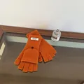 Detail of orange wool knit convertible mittens showing flip top and black button closure - Orange