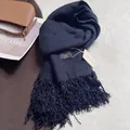 Detailed view of thick dark blue pashmina scarf with tassel trim and brand label - Navy Blue