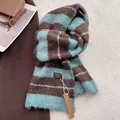 Detailansicht eines dicken gestreiften Wollschals mit Markenetikett und Strickstruktur - Seeblau