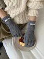 Dettaglio guanti in lana merino grigia a trecce con etichetta del marchio sul polso - Grigio