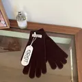 Detailed close-up of dark brown knit gloves with ribbed cuffs and branded fabric label - Coffee