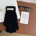 Close-up of black knitted gloves with brand label on a wooden desk with a laptop - Black