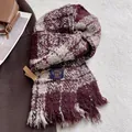 Detail shot of burgundy plaid scarf with tassels on textured carpet background - Burgundy