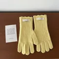 Detail von hellgelben Wollstrickhandschuhen mit gewellten Rüschenbündchen und Etiketten - Gelb