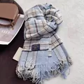 Detail of soft blue plaid cashmere-like scarf with thick fringes and woven brand label - Azure Blue